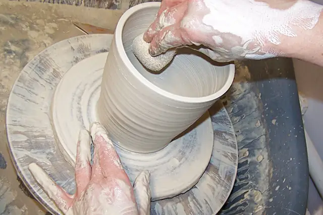 Hands throwing a pot on the wheel